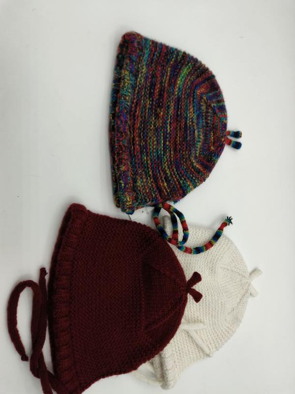 Trio de bonnets bébé tricotés main posés côte à côte en laine multicolore