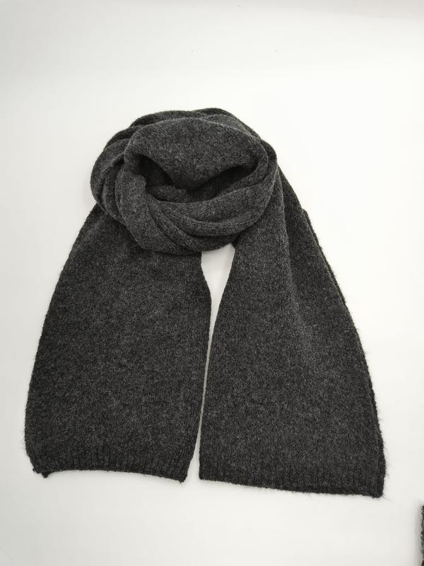 Écharpe tricotée gris foncé en maille épaisse dépliée sur fond blanc texture laine