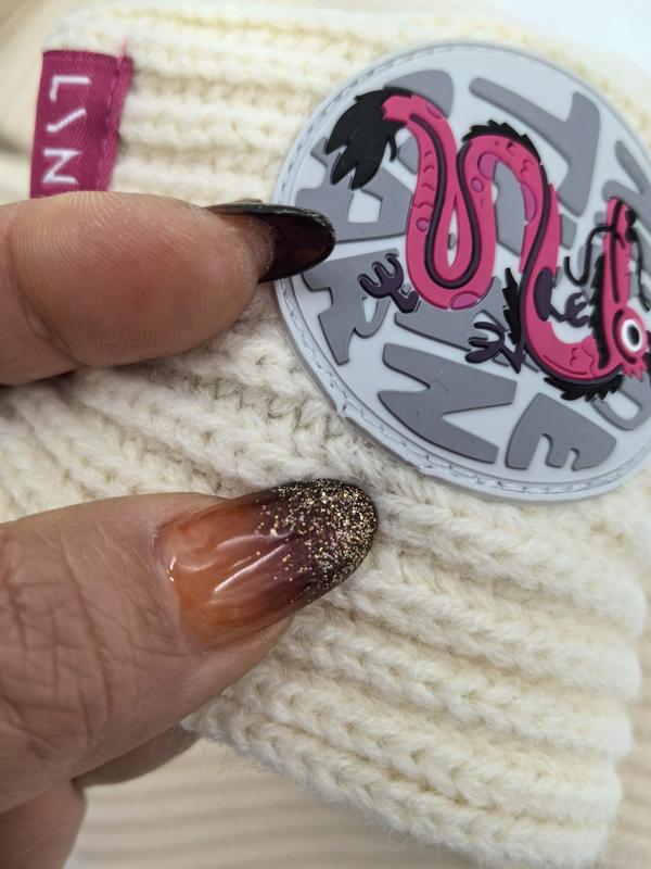 Bonnet hivernal crème tenu en main avec ongles pailletés
