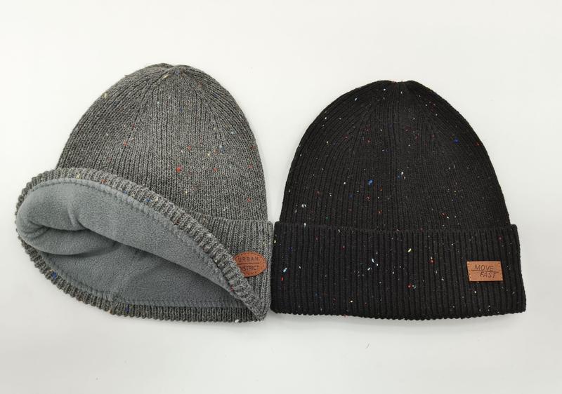 Deux bonnets maille chinée côte à côte : bonnet gris roulé doublé polaire et bonnet noir à revers avec patch cuir