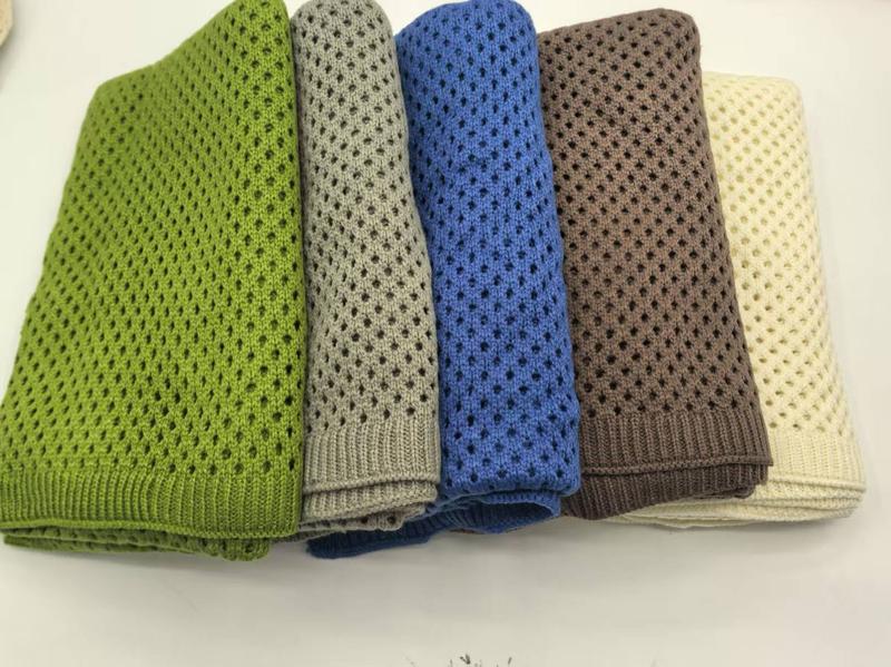Cinq plaids tricot coton ajouré pliés vert gris bleu marron crème empilés fond blanc toutes saisons