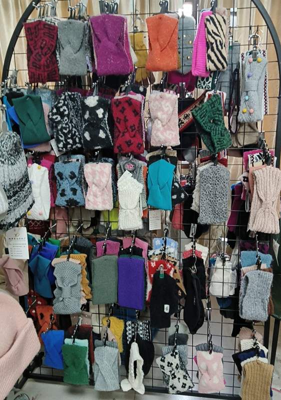 Grand présentoir boutique avec dizaines de gants mitaines sans doigts tricotés en couleurs motifs et textures variés pour l'hiver