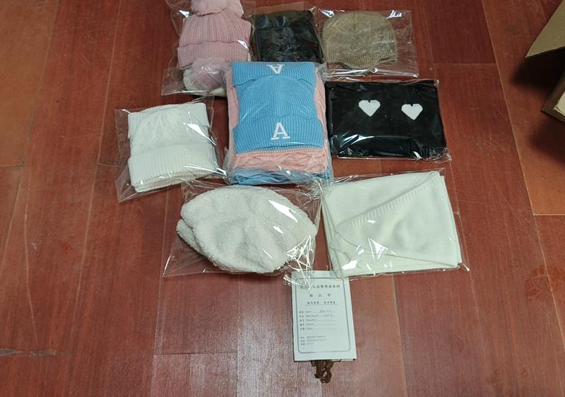 Lots emballés de bonnets et écharpes tricotés rose bleu noir crème et camel exposés sur parquet avec carte produit