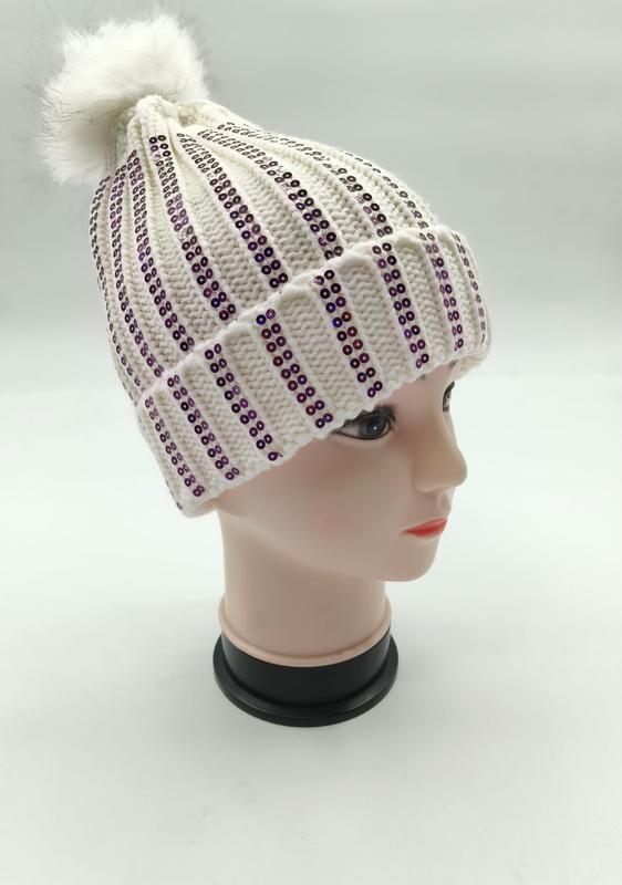 Bonnet côtelé blanc avec rayures verticales de sequins violets et pompon en fausse fourrure sur tête mannequin