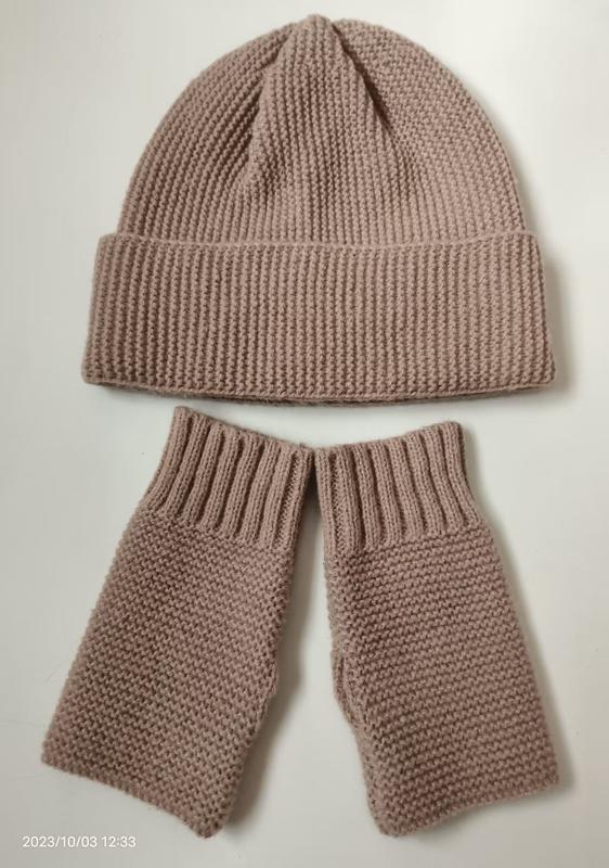 Bonnet côtelé et mitaines sans doigts rose poudré faits main posés à plat fond blanc