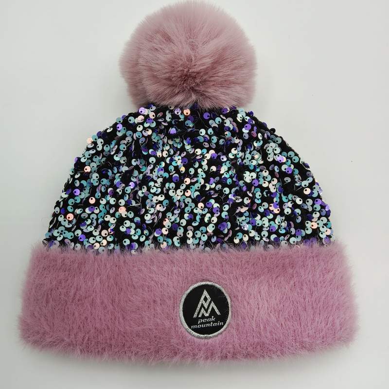Bonnet hiver rose à sequins irisés avec pompon oversize en fourrure synthétique rose et revers moelleux sur fond blanc