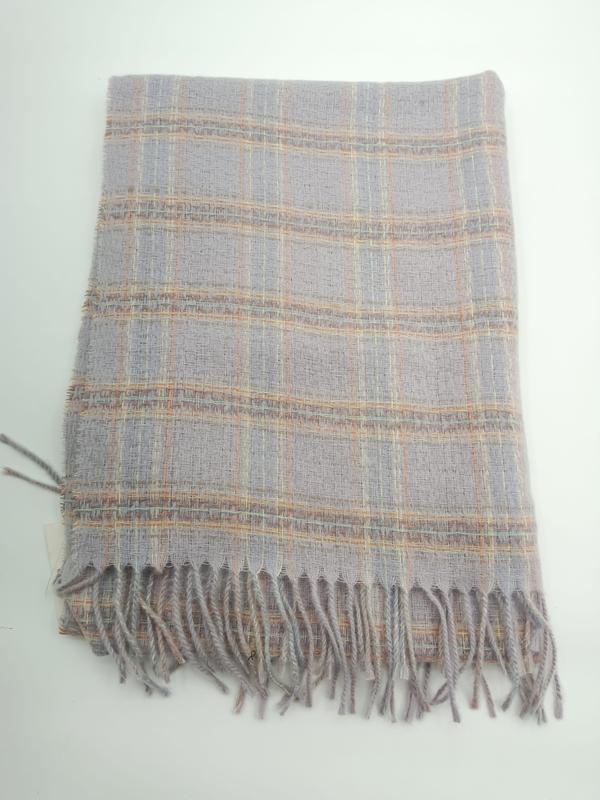 Plaid tissé plié gris clair avec motif carreaux pêche et doré et franges torsadées
