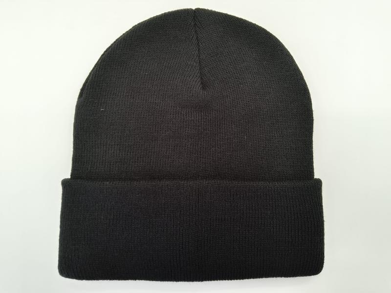 Bonnet noir côtelé à revers replié posé à plat sur fond blanc