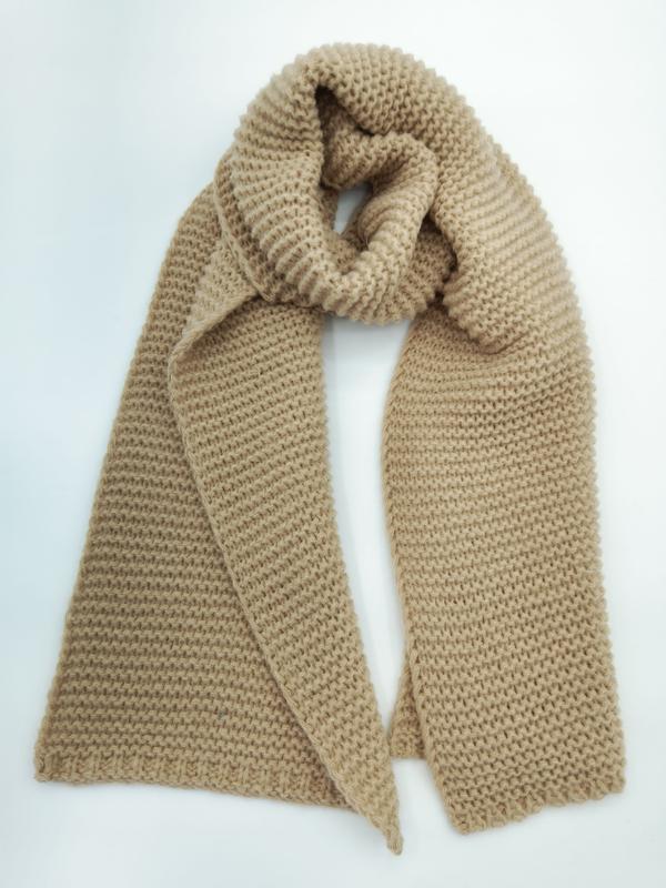 Écharpe grosse maille camel beige posée à plat avec motif point mousse texturé visible sur fond blanc