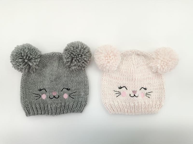 Deux bonnets bébé tricotés avec oreilles pompons et visage chat brodé
