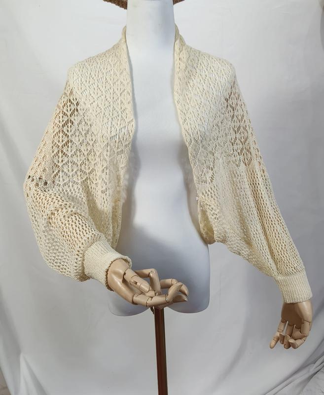 Boléro shrug crochet ivoire crème avec manches évêque volumineuses et poignets côtelés sur mannequin