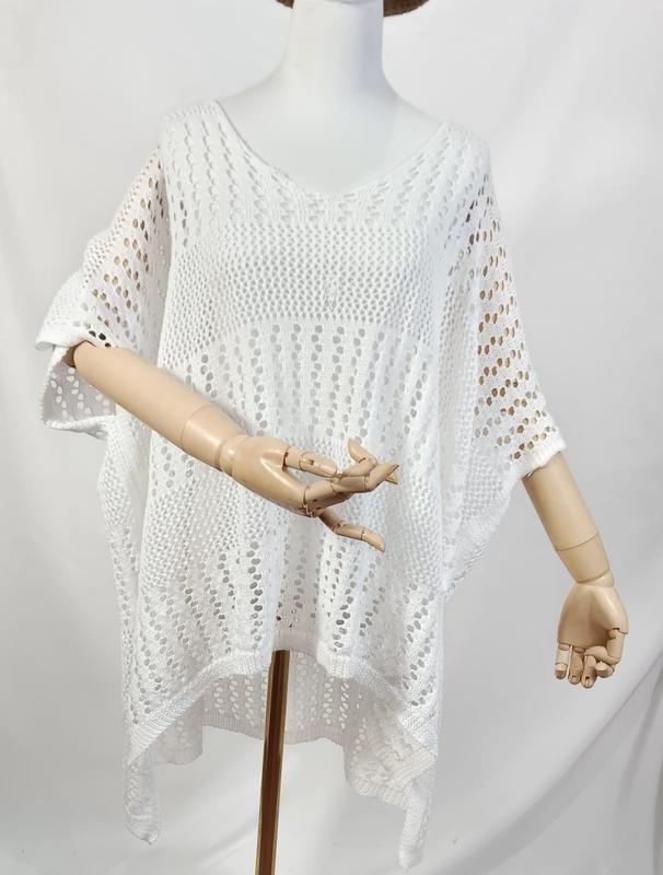 Poncho top crochet ajouré blanc oversize col V manches courtes sur mannequin aux mains en bois