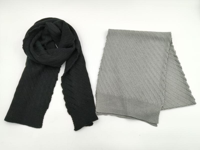Deux écharpes tricotées à plat : noire drapée et gris clair pliée avec motif chevrons et bordures côtelées
