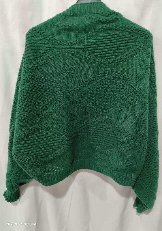 Dos d'un pull vert émeraude en grosse maille avec motif ajouré géométrique losange et ourlet côtelé sur mannequin