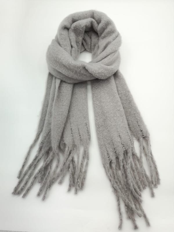Écharpe tricotée gris clair douce posée à plat avec longues franges aux extrémités