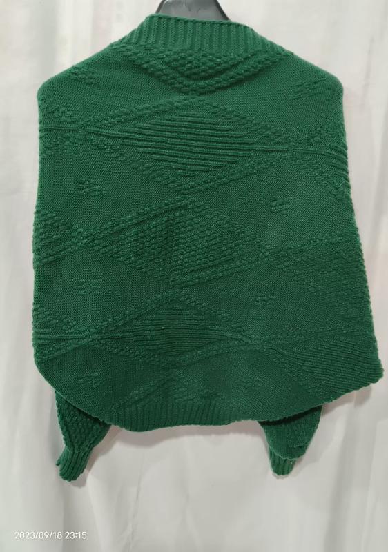 Dos d'un poncho vert émeraude en grosse maille avec texture losange géométrique en relief sur cintre