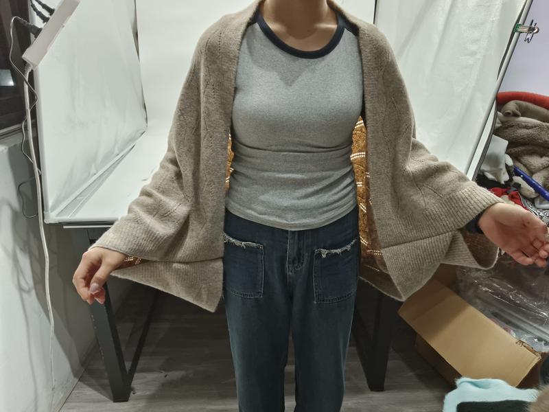 Femme portant un grand cardigan beige oversize en tricot avec manches amples sur haut gris côtelé et jean bleu