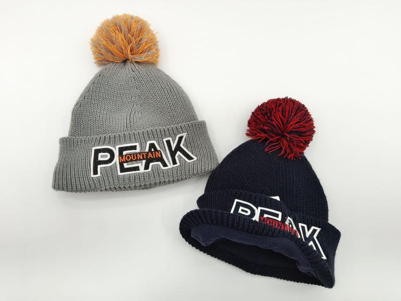 Deux bonnets gros tricot gris et marine avec logo Peak Mountain brodé et pompons colorés