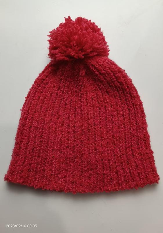Bonnet rouge en grosse maille côtelée avec grand pompon moelleux sur le dessus