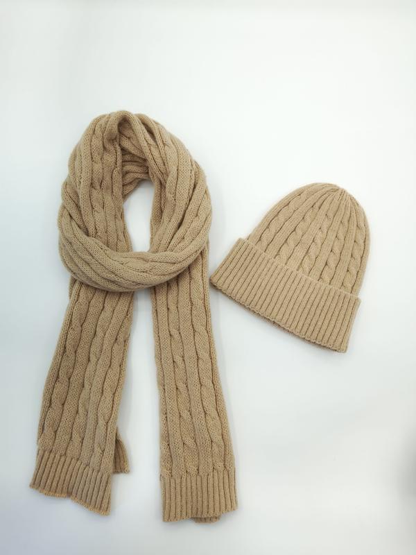 Écharpe torsadée camel tan enroulée à côté d'un bonnet assorti en tricot câble sur fond blanc