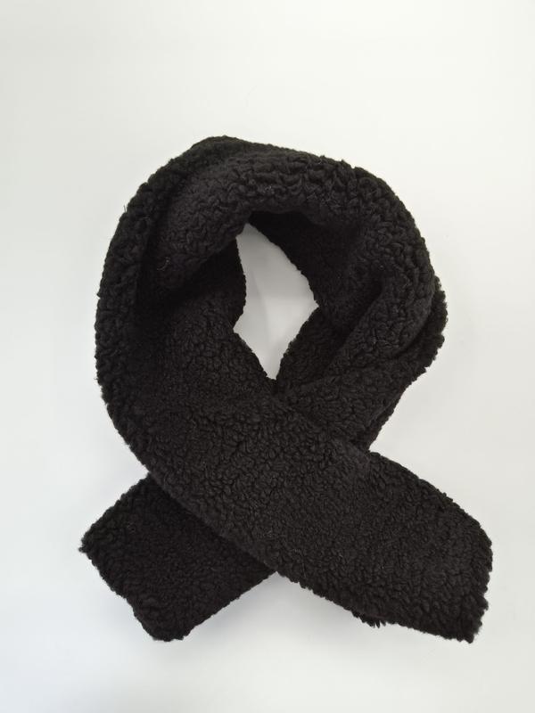 Écharpe sherpa noire bouclée et croisée sur fond blanc