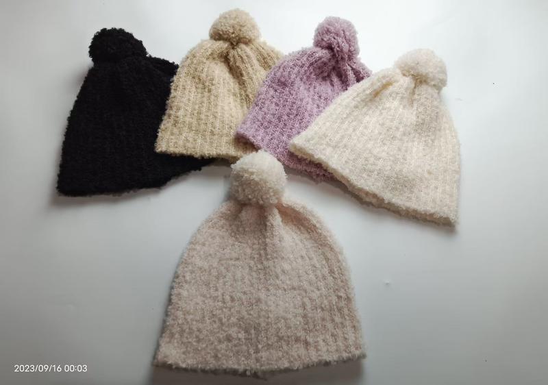 Cinq bonnets tricot pompons posés en éventail
