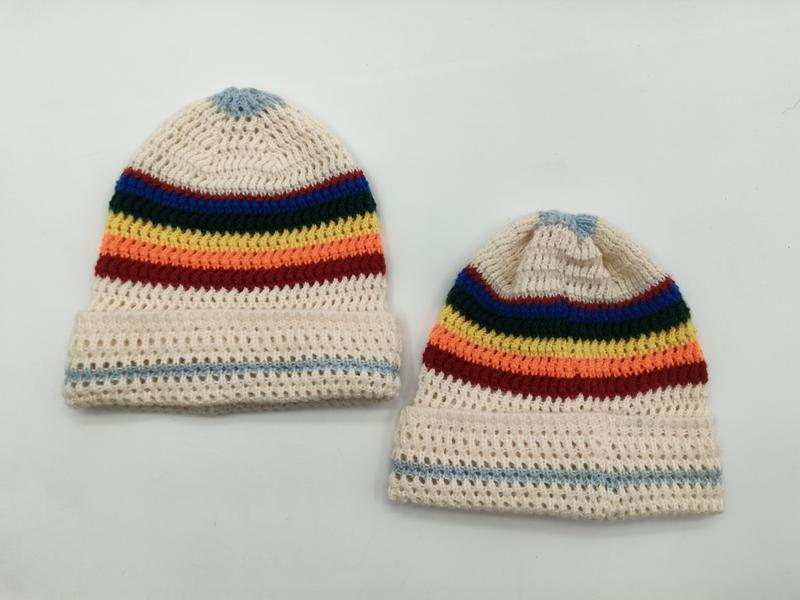 Deux bonnets crochet ajouré crème avec rayures arc-en-ciel multicolores et pompon bleu ciel
