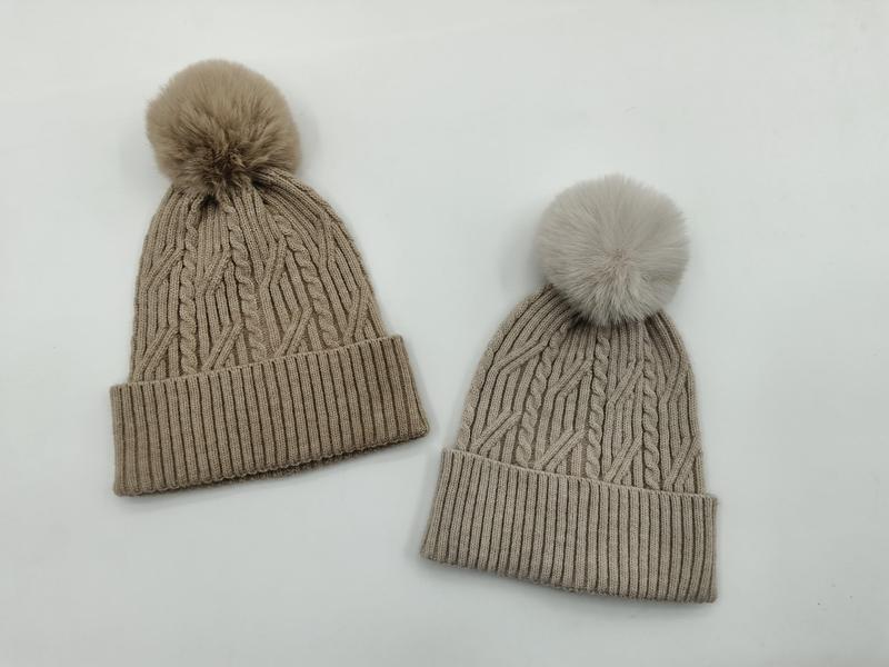 Deux bonnets en maille torsadée avec pompon en fourrure synthétique