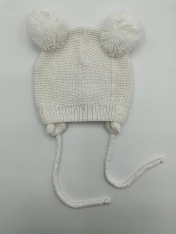 Bonnet tricoté ivoire pour bébé avec deux pompons moelleux sur le dessus et longs cordons
