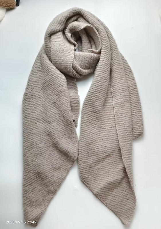 Écharpe tricot beige en maille côtelée posée en boucle sur fond blanc