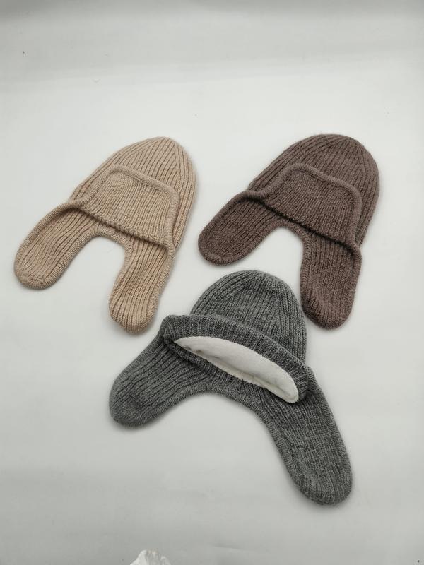Trois bonnets tricot côtelés cache-oreilles en beige marron et gris posés à plat fond blanc
