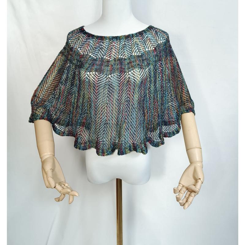 Poncho cape crochet filet multicolore arc-en-ciel sur mannequin aux mains articulées