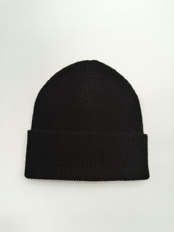 Bonnet noir en tricot côtelé avec large revers replié à plat sur fond blanc