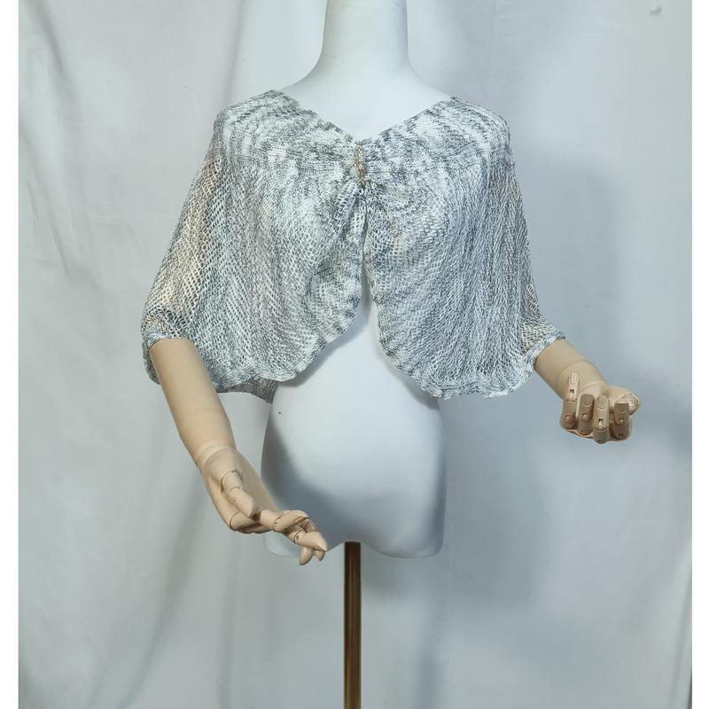 Mannequin portant une capelet voile transparente imprimé serpent gris avec fermeture broche décorative au col