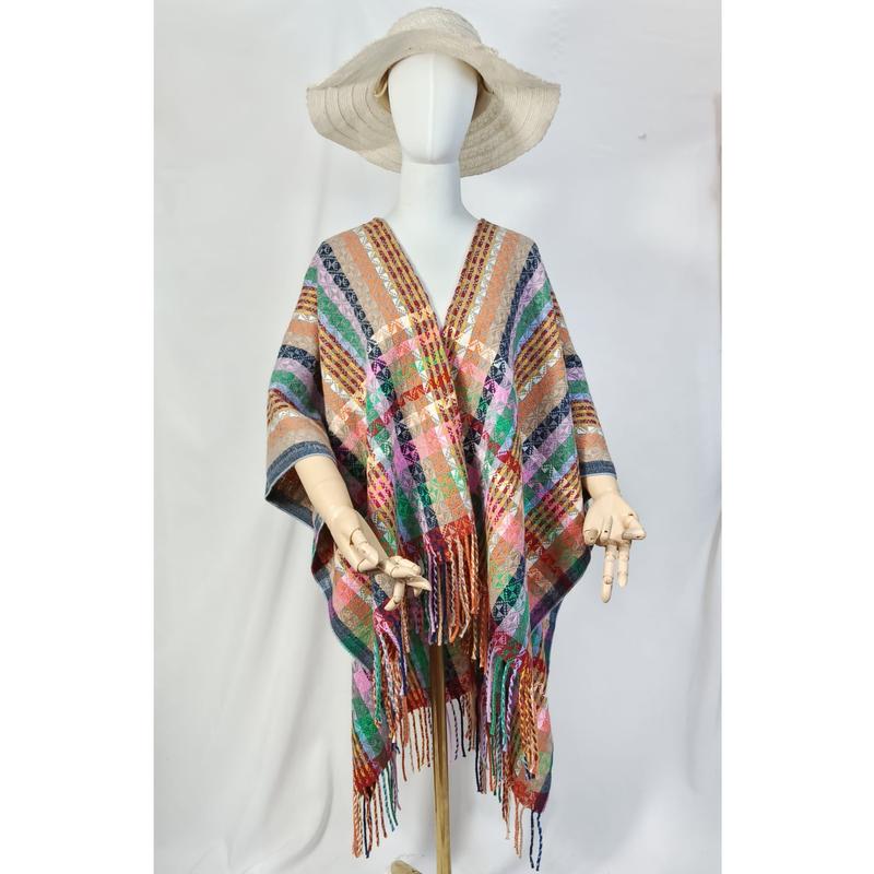 Mannequin portant un poncho tissé à carreaux multicolores avec frange et chapeau bords larges de paille fond blanc
