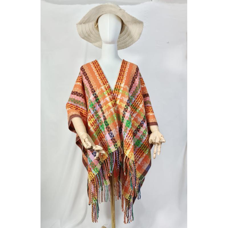Mannequin blanc portant un poncho tissé orange à motifs géométriques multicolores et longues franges avec chapeau naturel fond blanc
