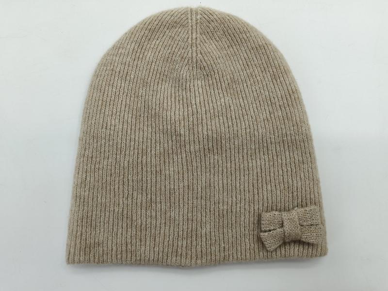 Bonnet beige en maille côtelée avec petit nœud tricoté sur le côté