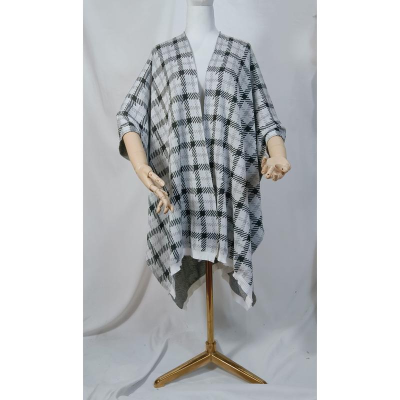 Cape poncho tricot pied-de-poule noir et blanc ouvert devant drapée sur mannequin avec trépied doré