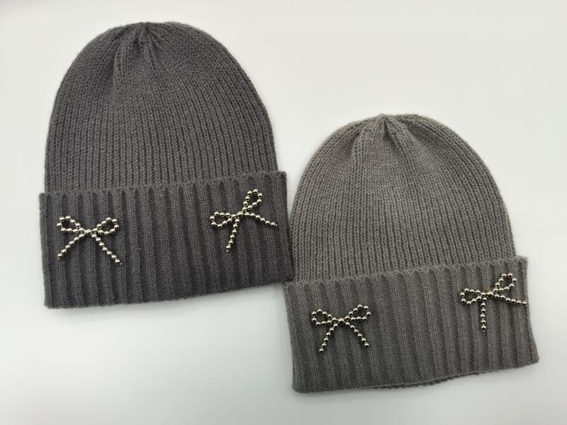 Deux bonnets tricot gris clair et gris foncé avec nœuds métal argenté perlé sur revers