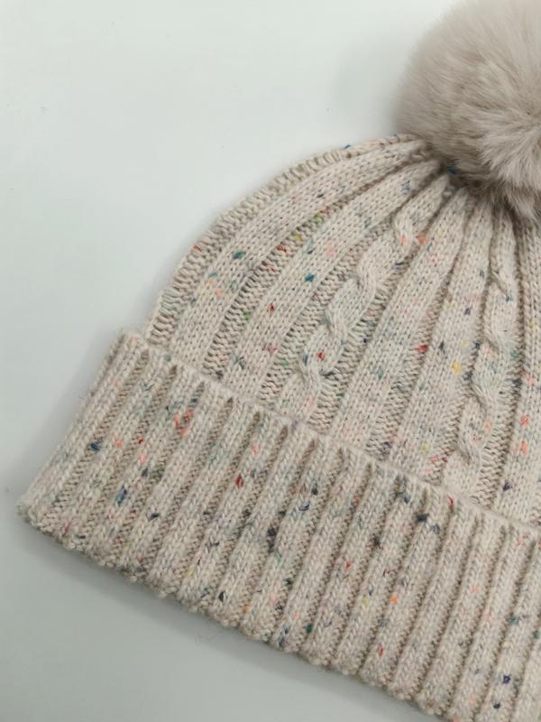 Gros plan bonnet torsadé crème chiné coloré avec pompon fausse fourrure moelleux et revers côtelé ajusté