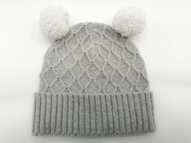 Bonnet bébé hiver gris en maille torsadée avec deux pompons blancs moelleux et revers côtelé
