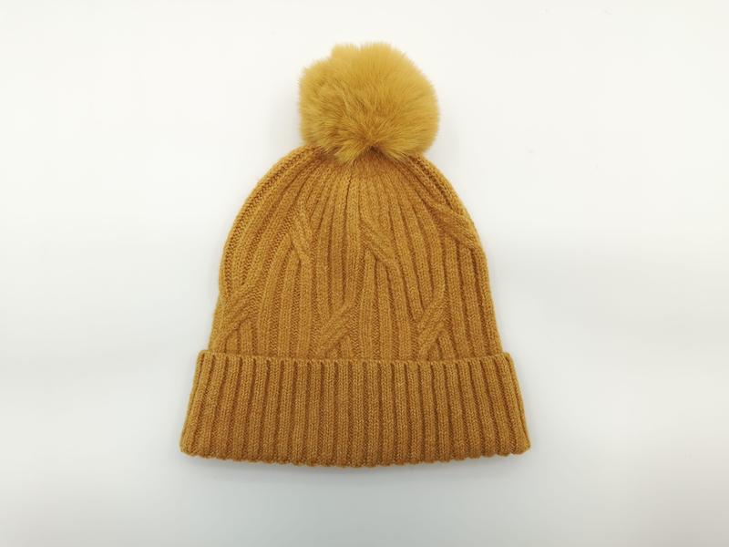Bonnet hiver moutarde en grosse maille torsadée avec grand pompon fausse fourrure et revers côtelé