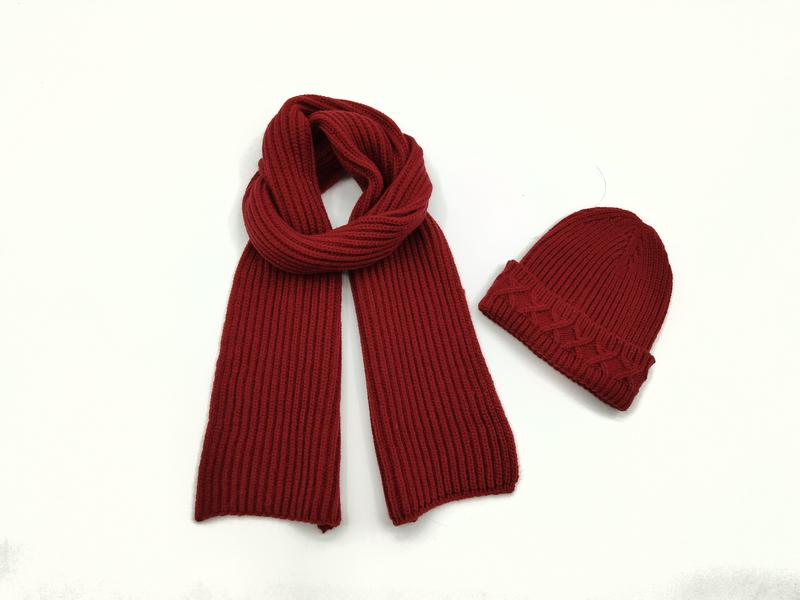 Écharpe côtelée rouge foncé et bonnet torsadé assorti posés côte à côte sur fond blanc