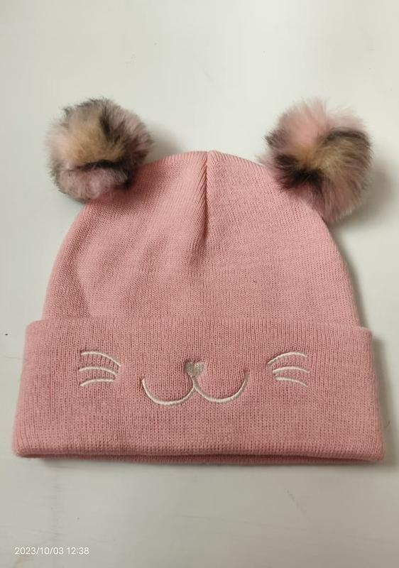 Bonnet rose tricoté enfant avec deux pompons fausse fourrure en oreilles de chat et moustaches brodées sur le revers
