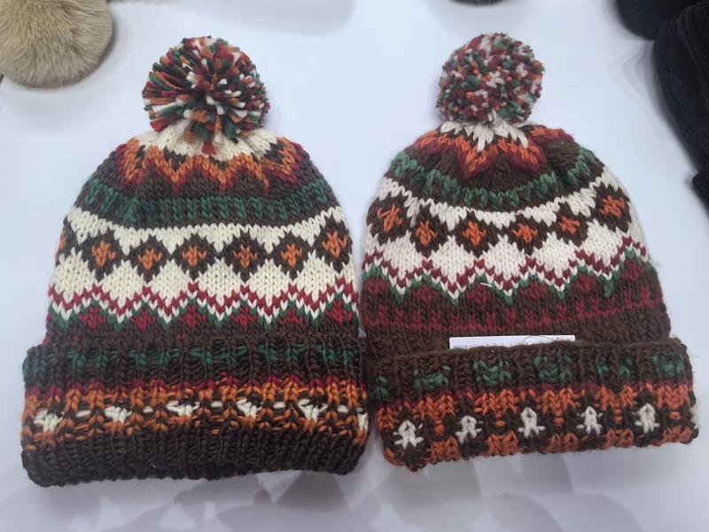 Deux bonnets Fair Isle jacquard pompon marron orange vert rouge crème tons automne posés à plat sur fond blanc